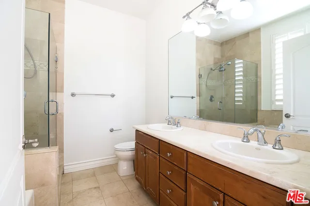 a bathroom with a double vanity sink toilet and shower