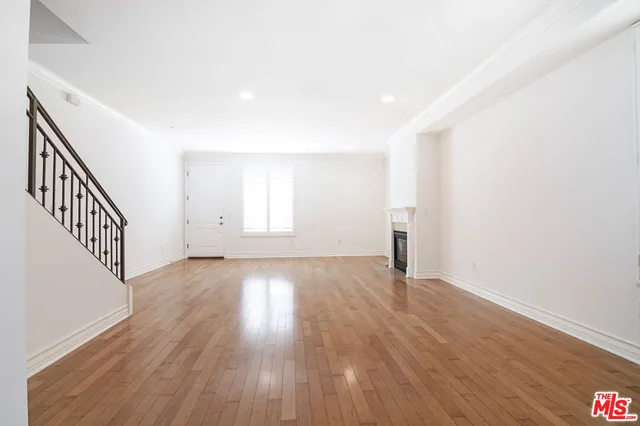 a view of an empty room with wooden floor and stairs