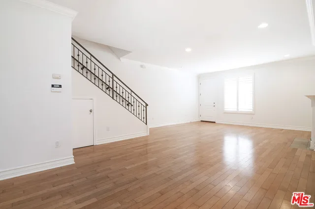 a view of an empty room with wooden floor and stairs