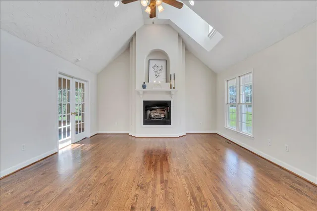 a view of an empty room with window and wooden floor