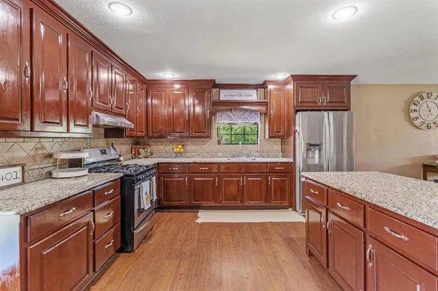 a kitchen with stainless steel appliances granite countertop wooden cabinets a stove top oven a sink and dishwasher