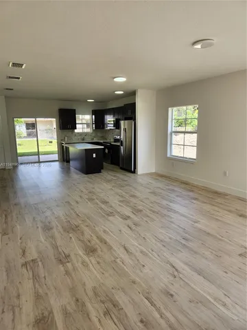 an empty room with kitchen view and a flat screen tv
