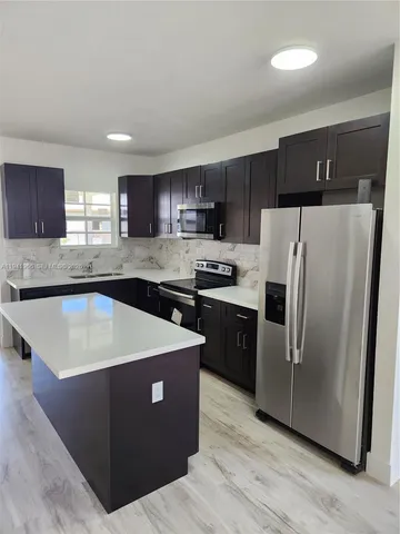 a kitchen with stainless steel appliances granite countertop a refrigerator a sink a stove a microwave and island