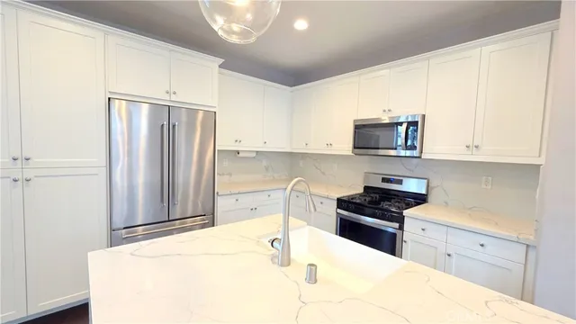 a kitchen with stainless steel appliances a refrigerator sink and white cabinets
