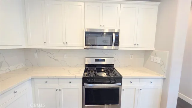 a kitchen with granite countertop white cabinets and stainless steel appliances