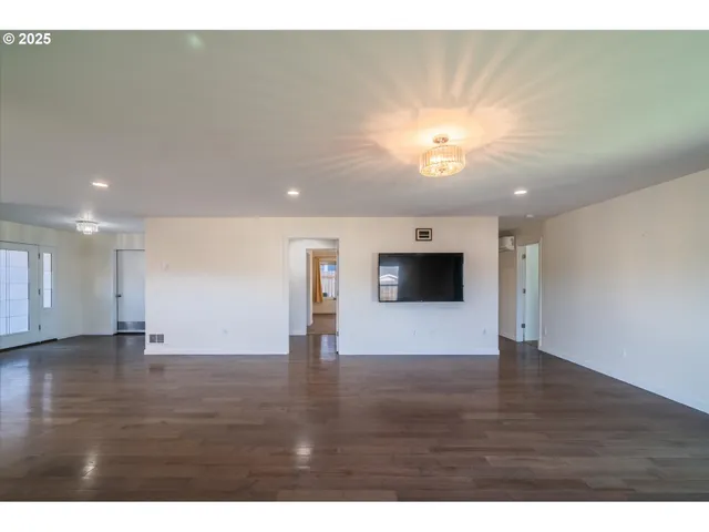a view of an empty room with window and wooden floor