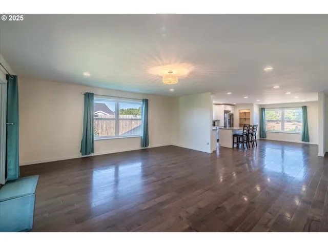 a view of empty room with wooden floor and floor to ceiling window