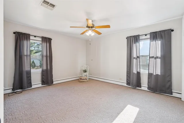 an empty room with windows and fan