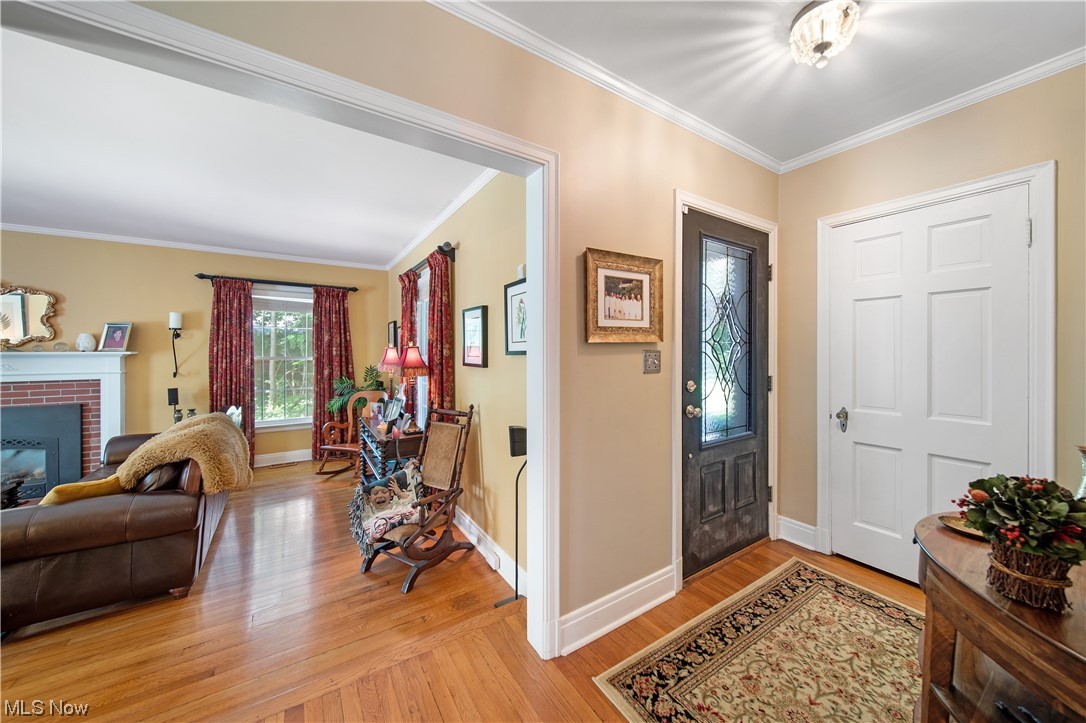 62 Fairfield Road Painesville, OH 44077 - Photo 11 of 34 Foyer entrance featuring ornamental molding, a fireplace, and light hardwood flooring