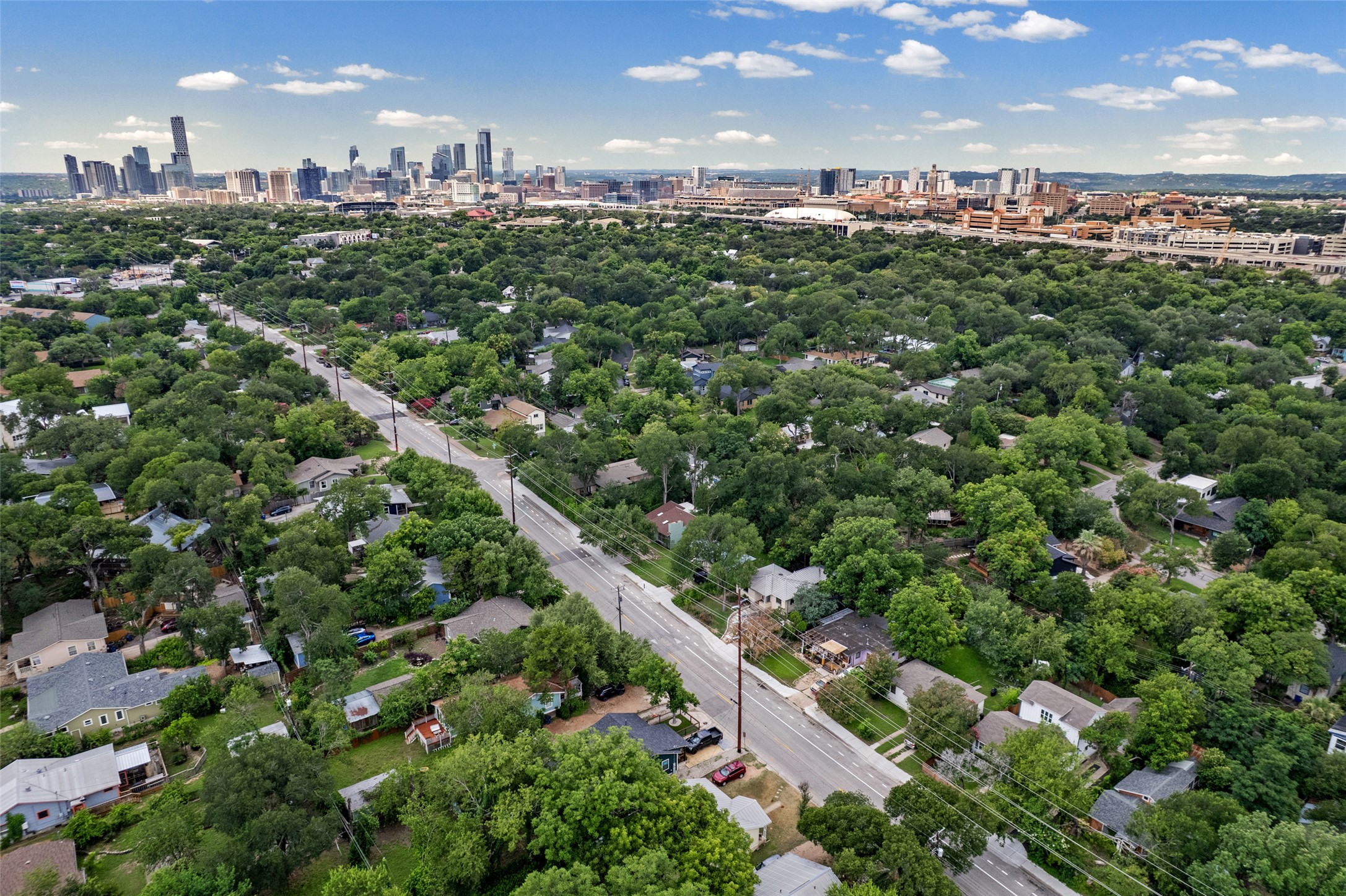3302 Cherrywood Road Austin, TX 78722 - Photo 25 of 26 A vibrant neighborhood with lush green trees stretching towards a dynamic cityscape on the horizon.