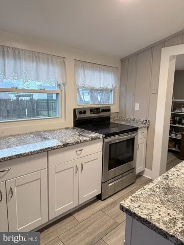 a kitchen with granite countertop a stove sink and cabinets