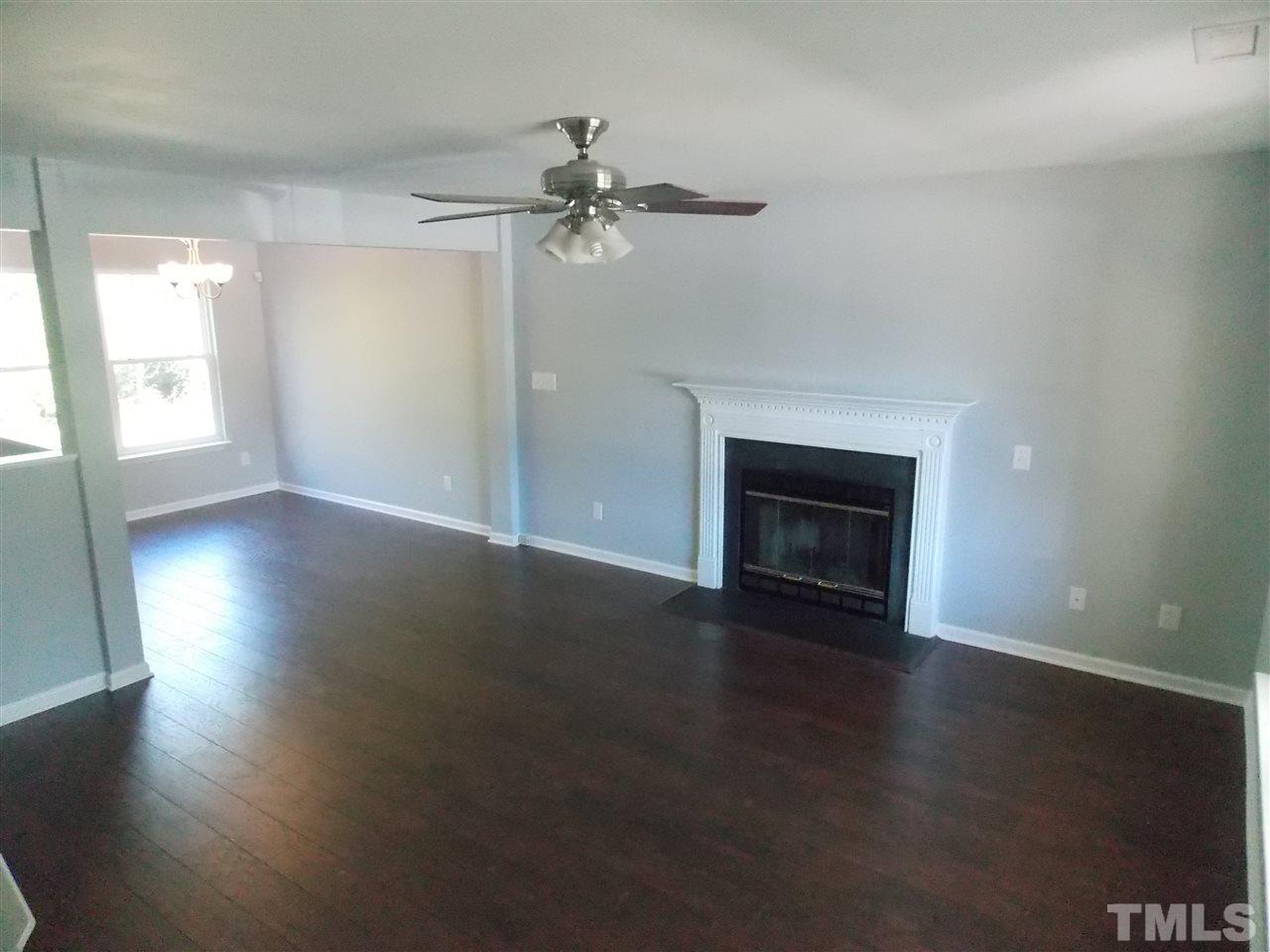 4101 Hopper Street Raleigh, NC 27616 - Photo 5 of 12 an empty room with wooden floor fireplace and windows