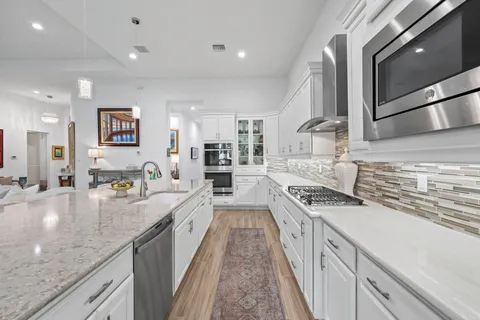 a large kitchen with stainless steel appliances granite countertop a stove and cabinets