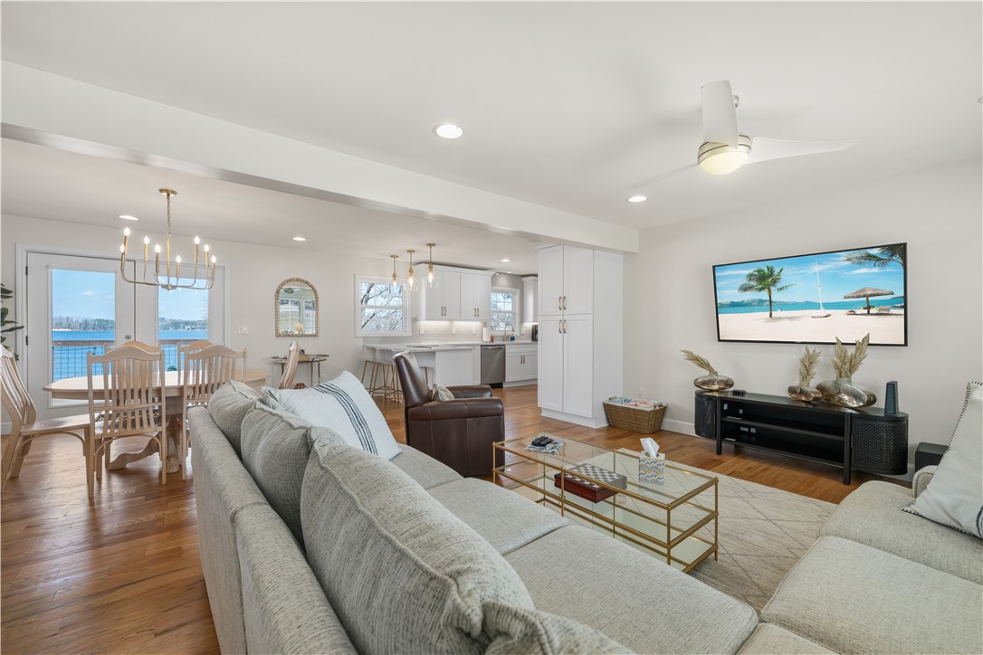 Bright and airy open-concept living space with beautiful hardwood floors and a view of the water.