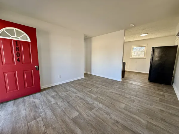 a view of an empty room with wooden floor and windows