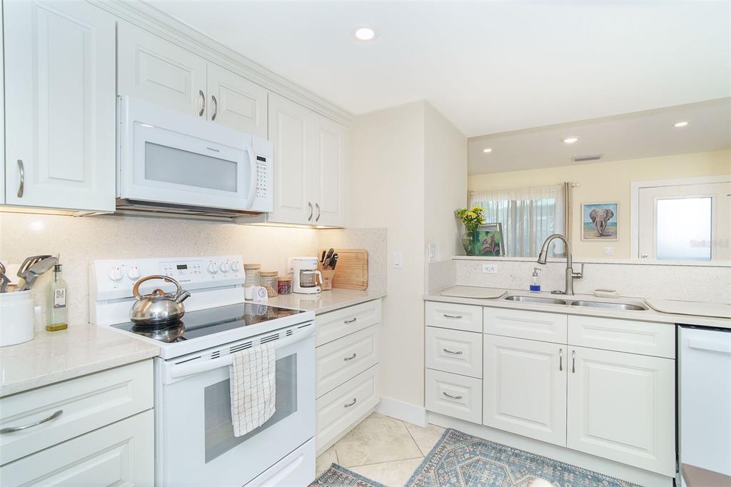 9200 Little Gasparilla, Unit 403 Boca Grande, FL 33921 - Photo 10 of 38 a kitchen with white cabinets appliances and a sink