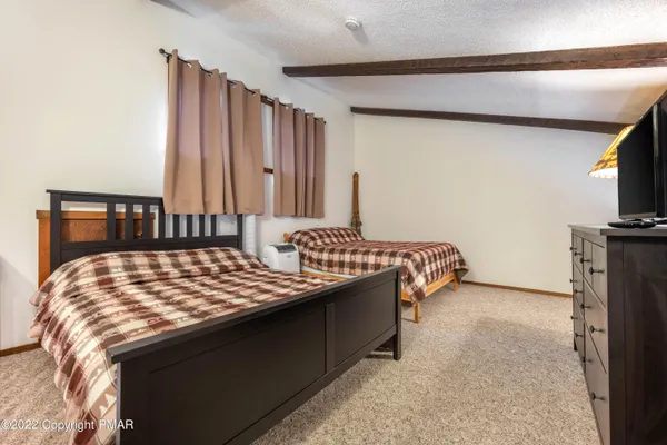 a bedroom with a bed and a flat tv screen on dresser