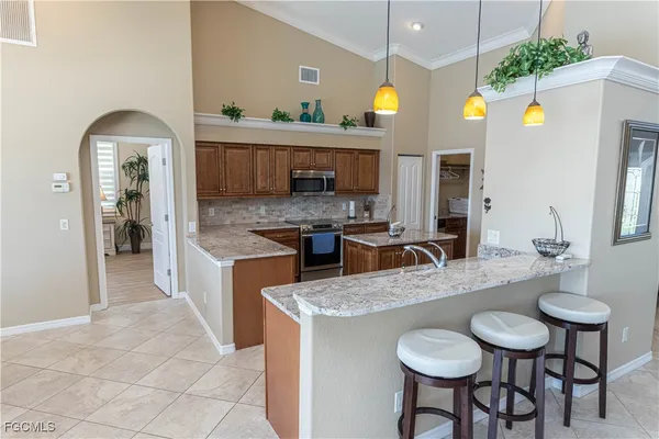 a kitchen with stainless steel appliances granite countertop a sink a stove and chairs