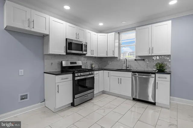 a kitchen with granite countertop white cabinets stainless steel appliances and a sink