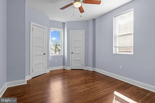 an empty room with wooden floor cabinet and windows