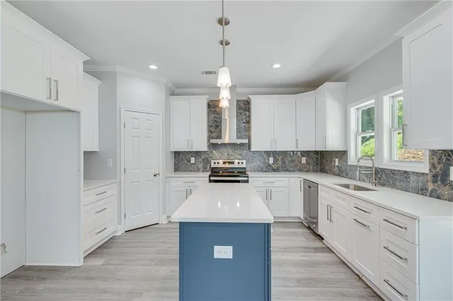 a large kitchen with stainless steel appliances kitchen island granite countertop a stove a sink a refrigerator and white cabinets with wooden floor