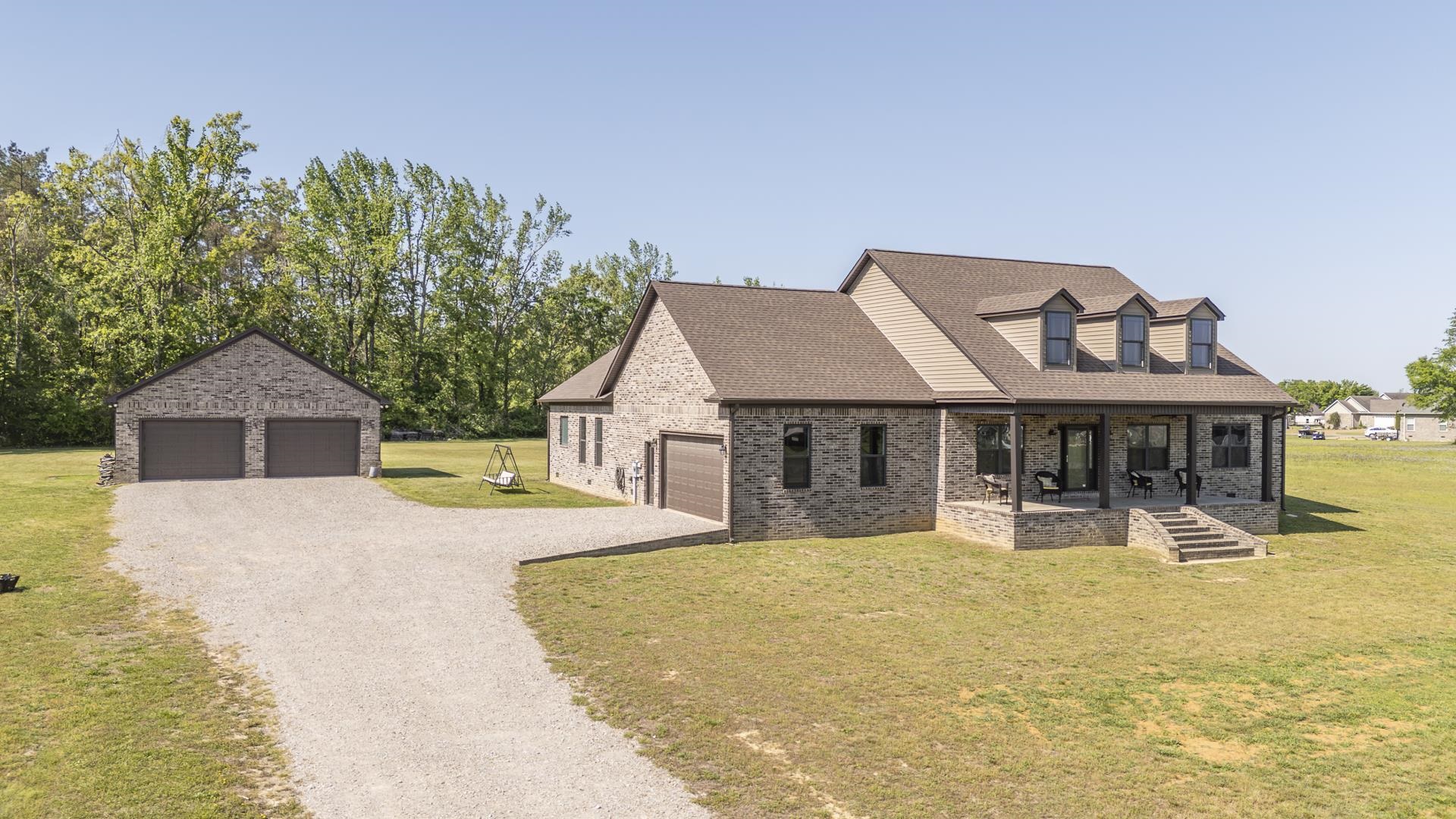 170 Kirk Cove Adamsville, TN 38310 - Photo 2 of 39 Cape cod house featuring a front yard, a porch, a shingled roof, a detached garage, and brick siding