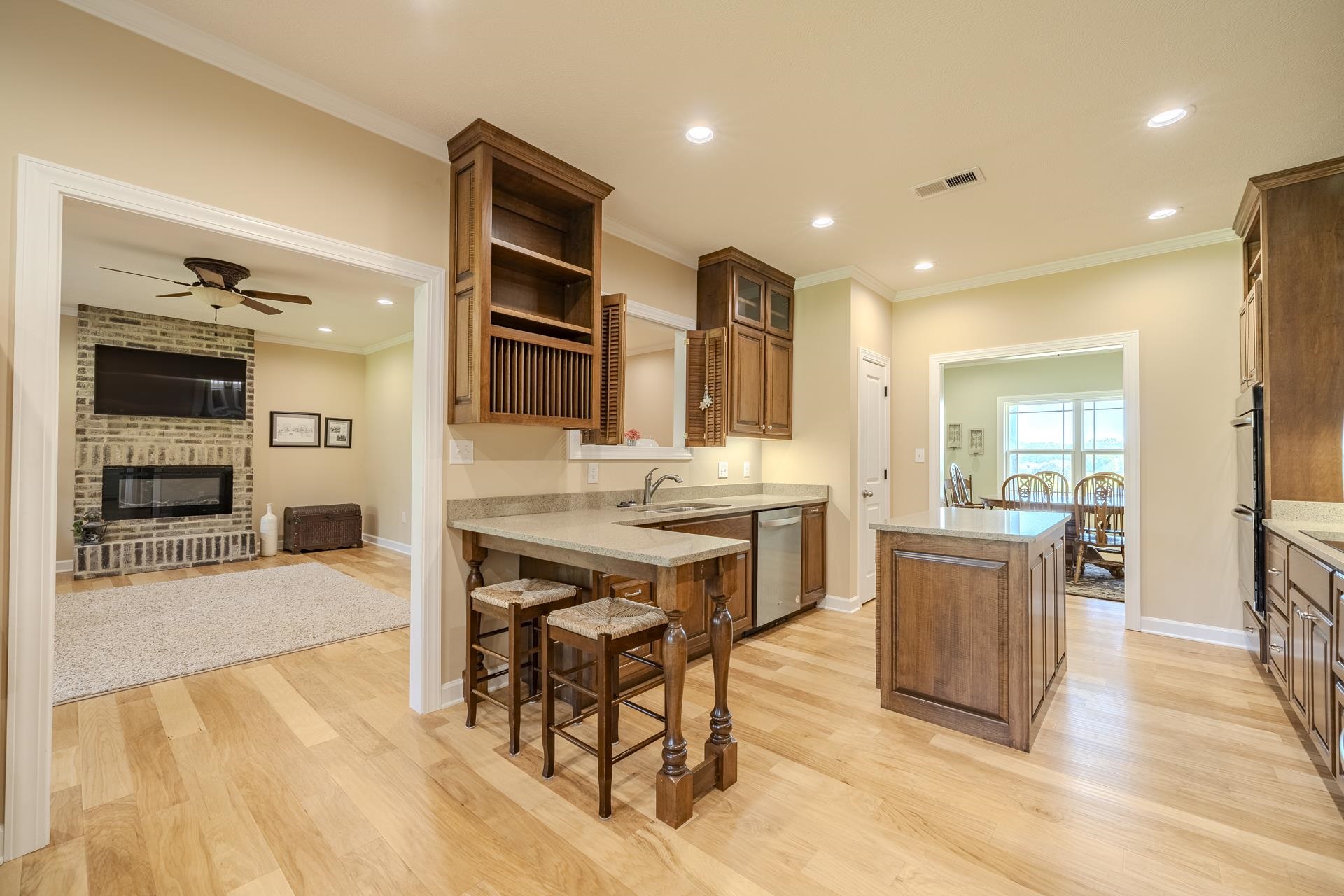 170 Kirk Cove Adamsville, TN 38310 - Photo 6 of 39 Kitchen featuring a fireplace, a center island, light wood finished floors, light stone counters, and wood finish cabinets
