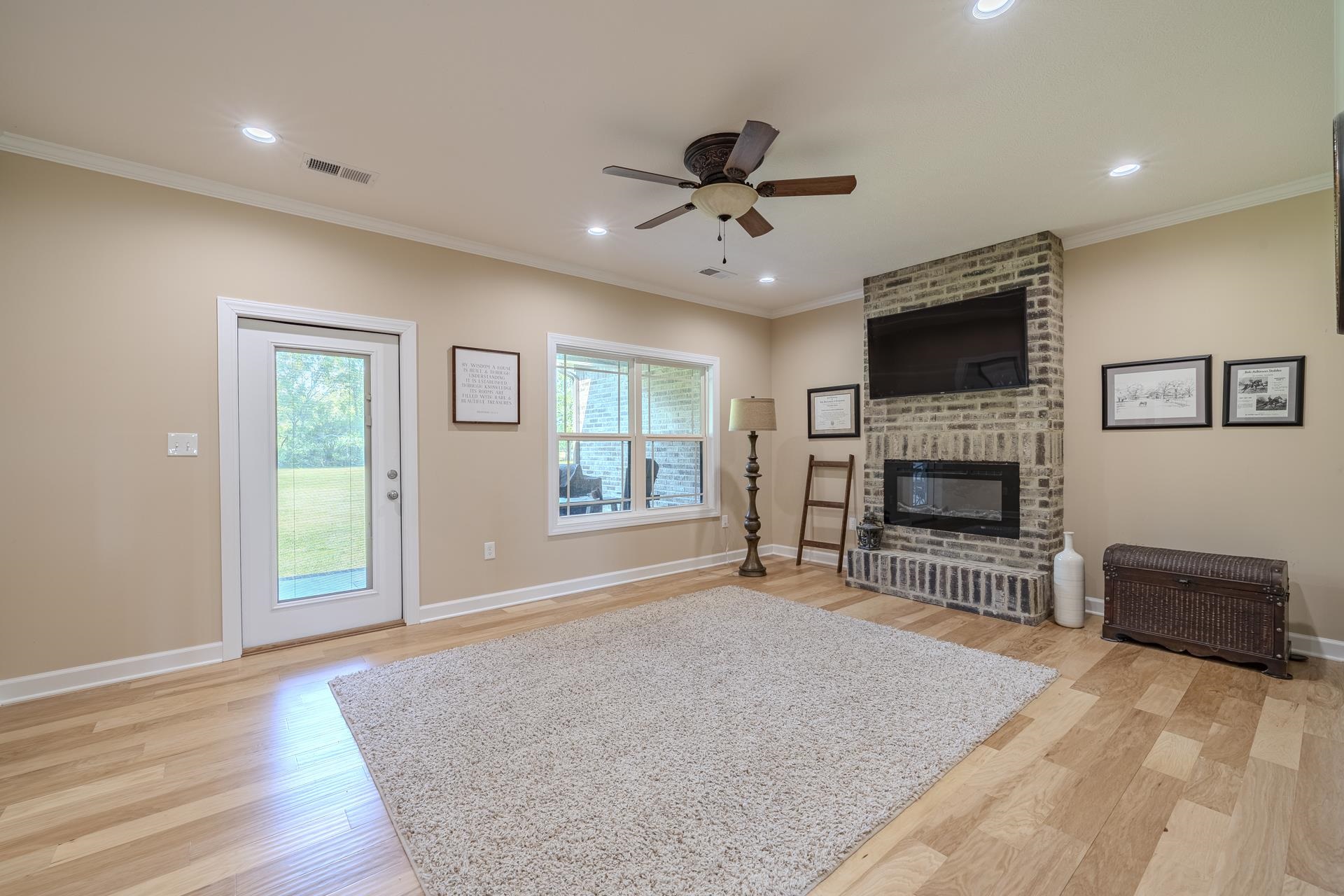 170 Kirk Cove Adamsville, TN 38310 - Photo 10 of 39 Living area featuring a ceiling fan, light wood-style flooring, a brick fireplace, ornamental molding, and recessed lighting