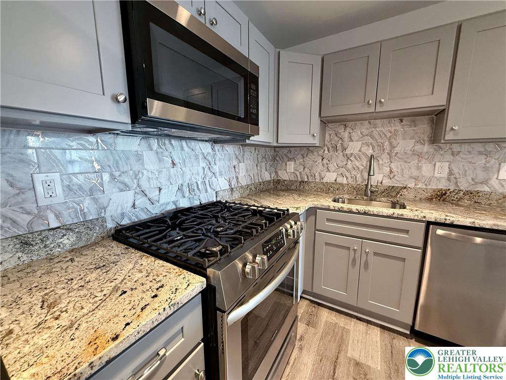 938 East 4th Street, Unit G03 Bethlehem, PA 18015 - Photo 17 of 30 a kitchen with granite countertop wooden cabinets and a stove top oven