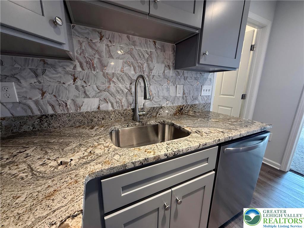938 East 4th Street, Unit G03 Bethlehem, PA 18015 - Photo 18 of 30 a kitchen with granite countertop a sink dishwasher a stove and a microwave oven with cabinets
