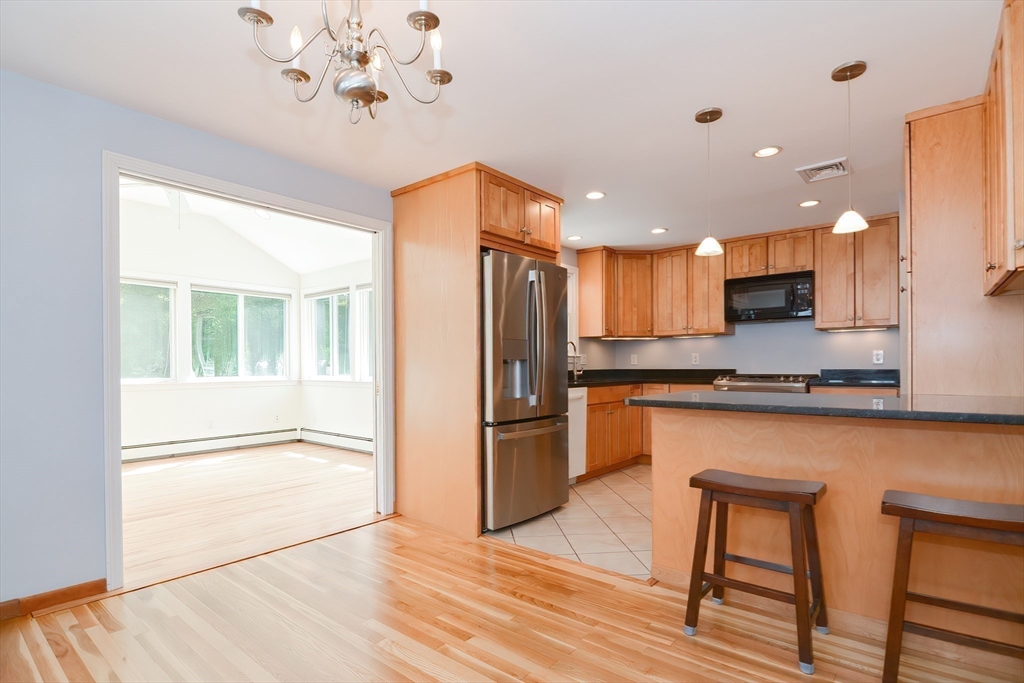 16 August Drive Framingham, MA 01701 - Photo 7 of 27 a kitchen with stainless steel appliances granite countertop a refrigerator a sink dishwasher a stove and a dining table with wooden floor