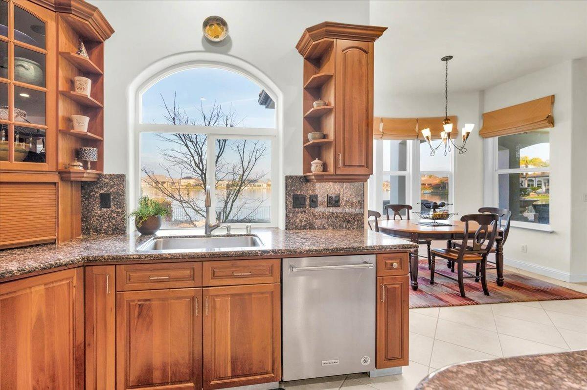 4574 North Quail Lake Drive Clovis, CA 93619 - Photo 21 of 77 a kitchen with kitchen island granite countertop a stove a sink a dining table and chairs with wooden floor