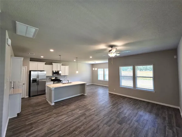 a view of a kitchen with kitchen island wooden floors wooden floor and stainless steel appliances