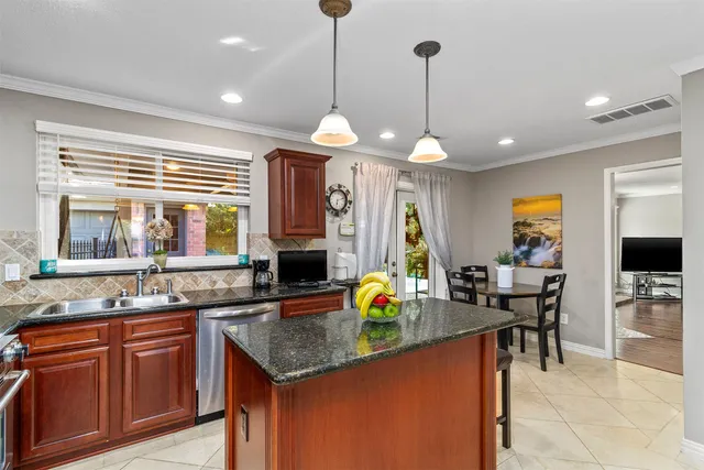 a kitchen with stainless steel appliances granite countertop a stove a sink a dining table chairs and chandelier
