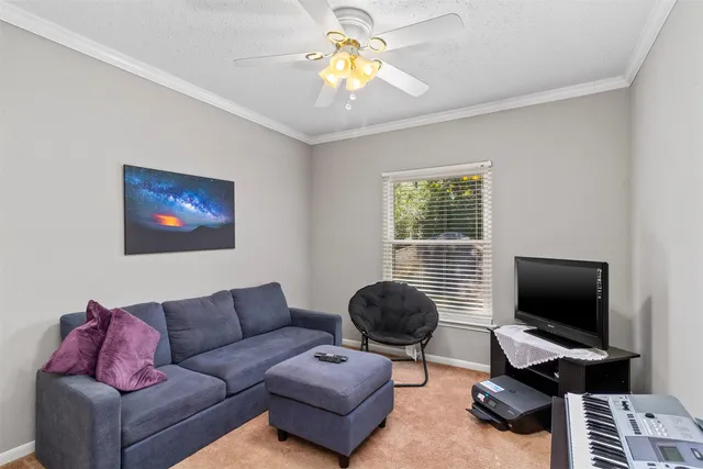 a living room with furniture a ceiling fan and a window