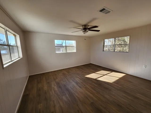 a view of an empty room with a window and wooden floor