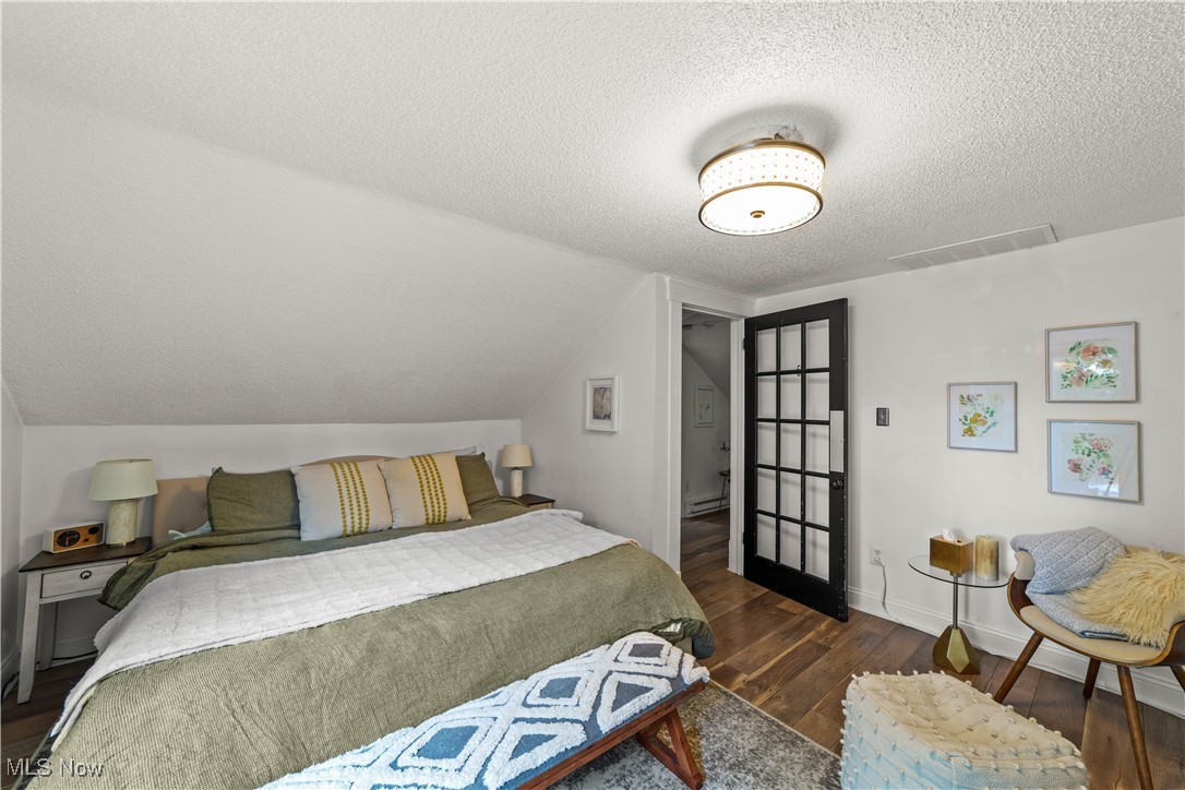 14420 Superior Road Cleveland, OH 44118 - Photo 29 of 44 Bedroom featuring a textured ceiling, wood finished floors, lofted ceiling, a baseboard radiator, and baseboards