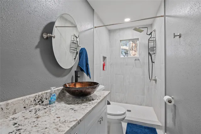 a bathroom with a granite countertop sink a toilet and a shower