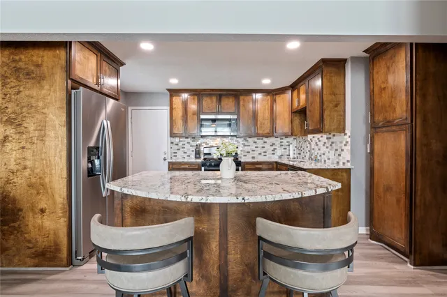 a kitchen with stainless steel appliances granite countertop a sink a stove and a refrigerator
