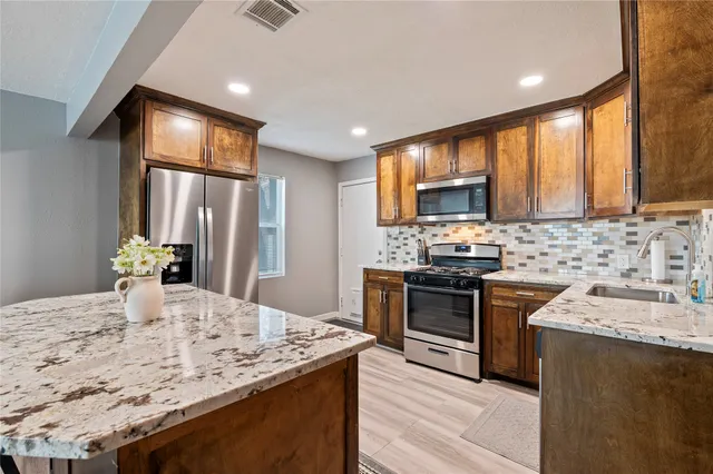 a kitchen with stainless steel appliances granite countertop a sink stove and refrigerator