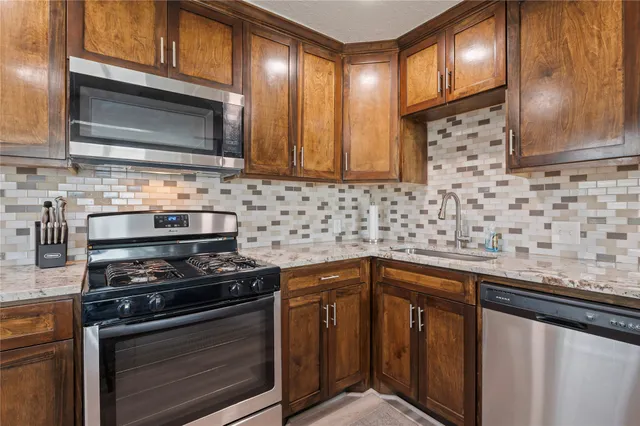 a kitchen with stainless steel appliances a stove microwave and sink