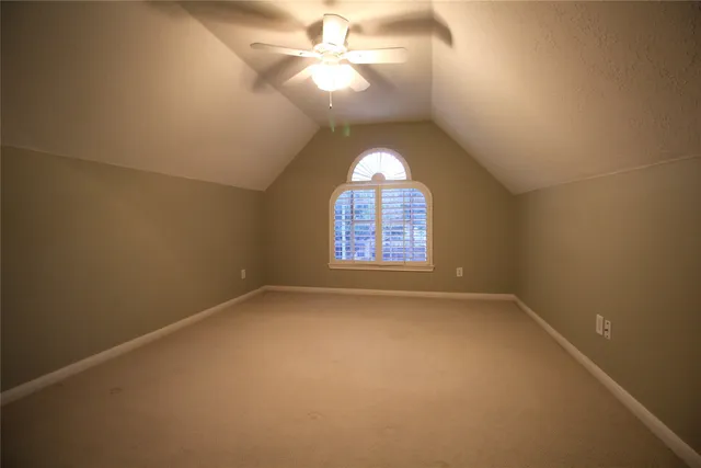 an empty room with a window and a chandelier fan