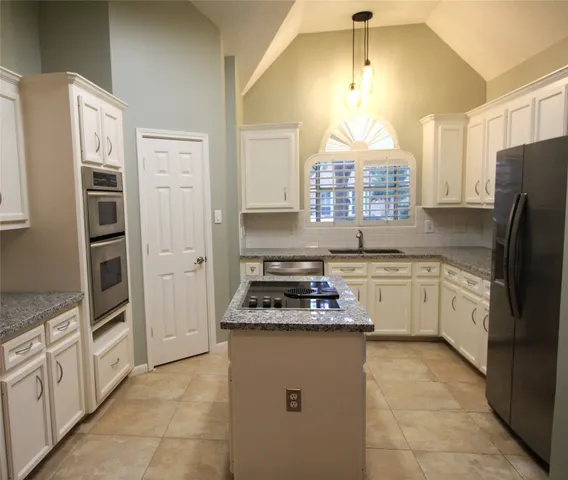 a kitchen with granite countertop a refrigerator sink and oven