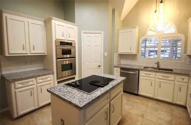 a kitchen with granite countertop a sink stove and cabinets