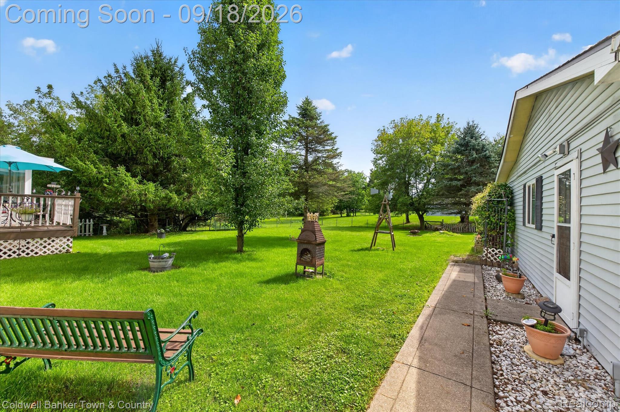 4442 McGunn Road Howell, MI 48843 - Photo 39 of 63 Expansive green lawn, mature trees, side patio with gravel landscaping, and a multi-level wood deck