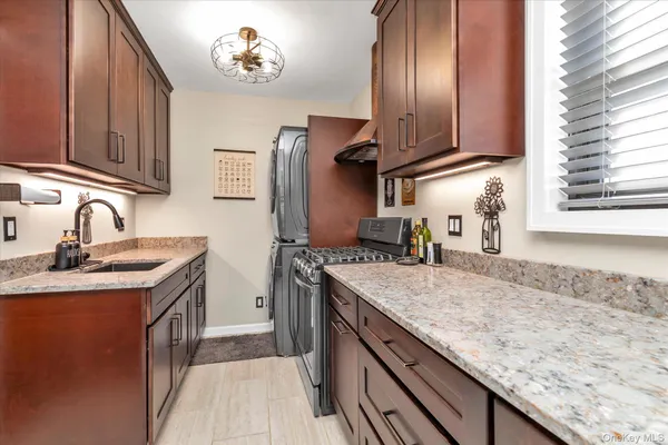 a kitchen with granite countertop stainless steel appliances a sink stove and cabinets