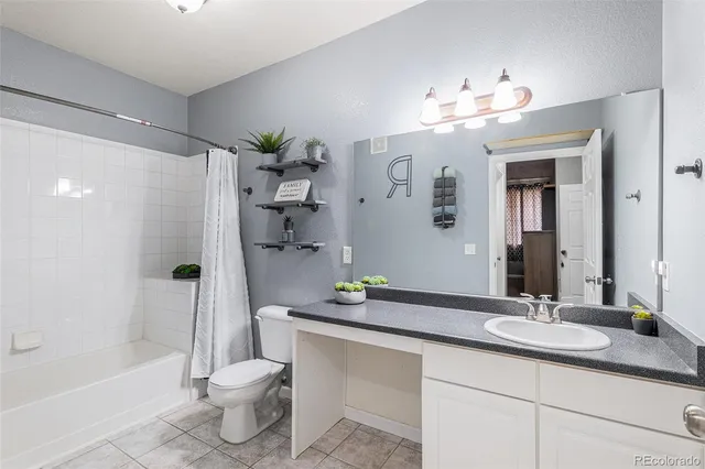a bathroom with a granite countertop sink a toilet a mirror a bathtub and shower