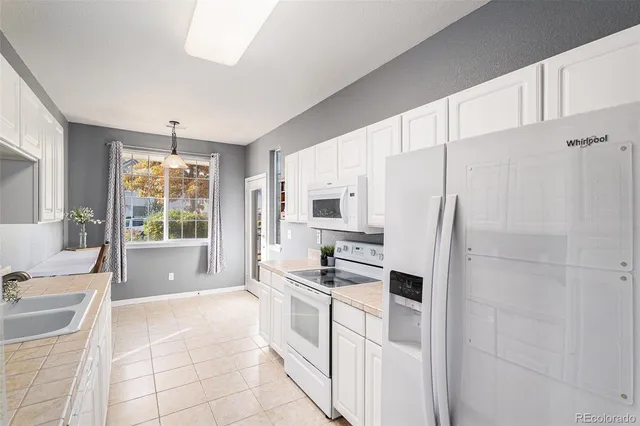 a large white kitchen with cabinets a sink a window and stainless steel appliances