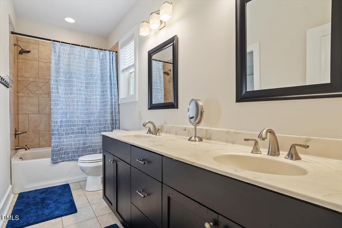 31 River View Court Timberlake, NC 27583 - Photo 30 of 44 a bathroom with a double vanity sink a toilet a mirror and shower