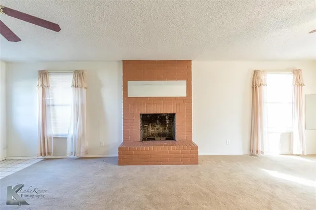 an empty room with a fireplace and windows